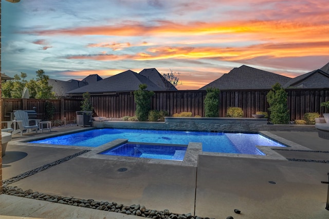 pool at dusk with an in ground hot tub, a patio area, a fenced backyard, and a fenced in pool