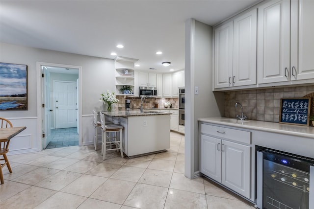 kitchen featuring wine cooler, stainless steel appliances, a sink, white cabinetry, and open shelves