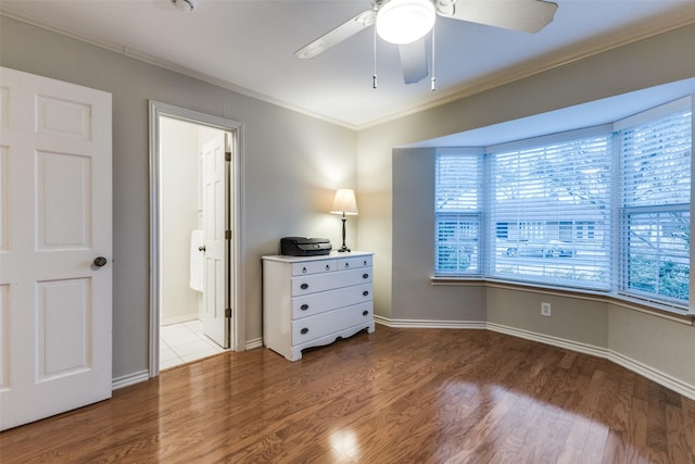 bedroom with ornamental molding, a ceiling fan, ensuite bath, wood finished floors, and baseboards