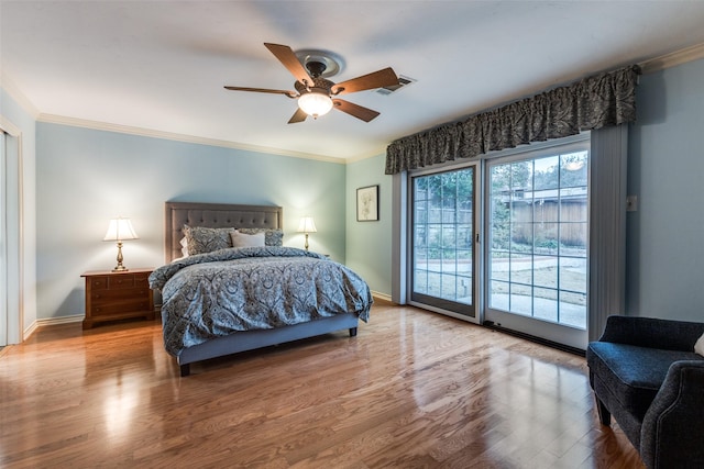 bedroom featuring baseboards, visible vents, wood finished floors, access to exterior, and crown molding