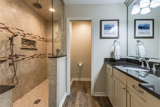 full bathroom featuring baseboards, walk in shower, wood finished floors, and vanity