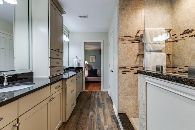 kitchen featuring dark wood-style floors, dark stone countertops, visible vents, and a sink