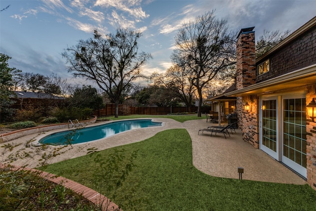 pool at dusk with a fenced in pool, a fenced backyard, a patio, and a lawn