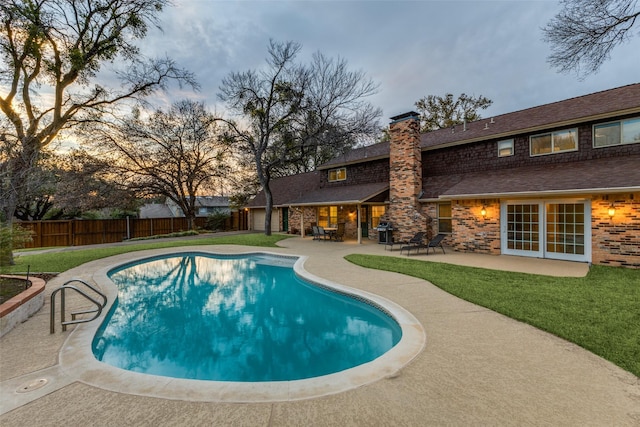 pool at dusk featuring a fenced in pool, a yard, a patio, grilling area, and a fenced backyard