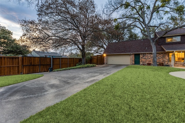 exterior space with driveway, a garage, fence, and a front lawn