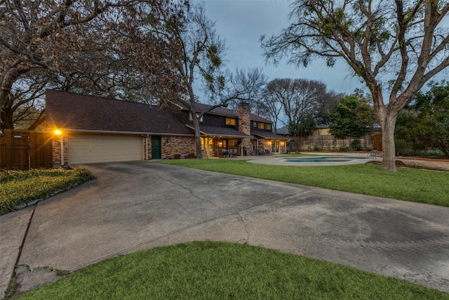 view of front of house with a chimney, fence, a garage, driveway, and a front lawn