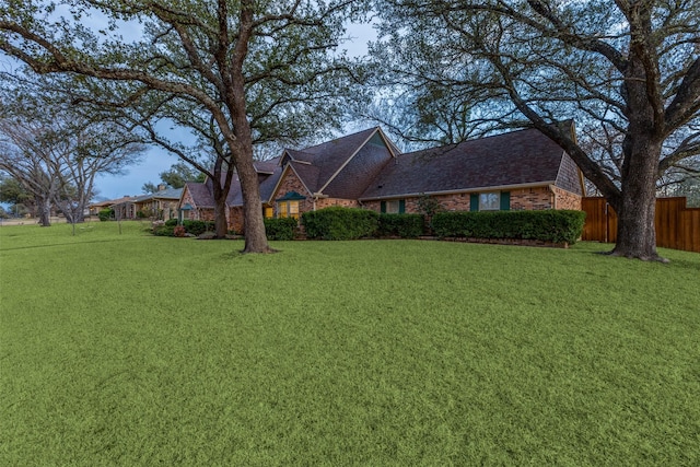 view of front of house featuring brick siding, fence, and a front yard