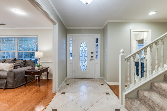 foyer featuring light tile patterned flooring, stairway, a wealth of natural light, and ornamental molding