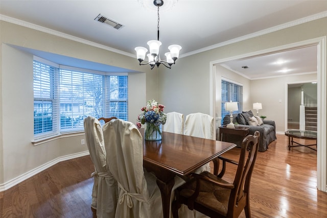 dining area with a chandelier, visible vents, crown molding, and wood finished floors