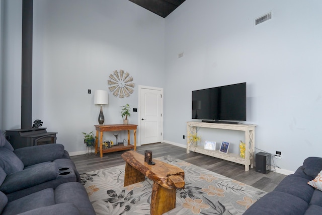 living room featuring a wood stove, baseboards, visible vents, and wood finished floors