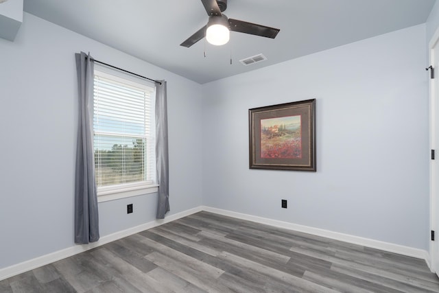 unfurnished room featuring ceiling fan, wood finished floors, visible vents, and baseboards