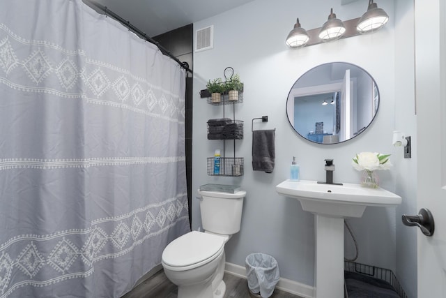 full bathroom with toilet, a shower with shower curtain, wood finished floors, visible vents, and baseboards