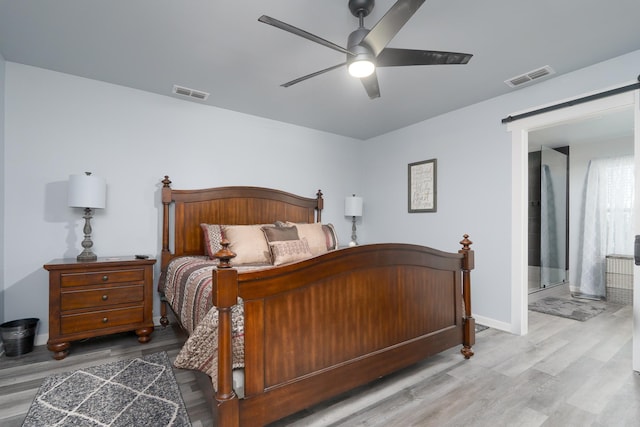 bedroom with a barn door, wood finished floors, and visible vents