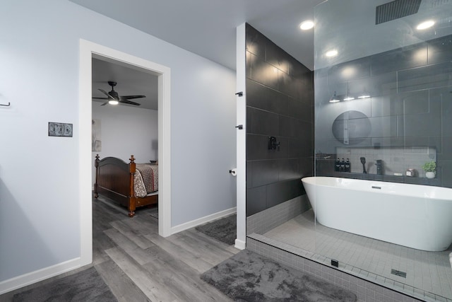 bathroom with tile walls, a soaking tub, ensuite bath, wood finished floors, and baseboards