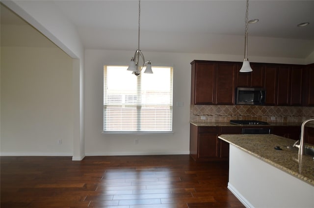 kitchen featuring black cooktop, dark wood-style floors, tasteful backsplash, stainless steel microwave, and pendant lighting