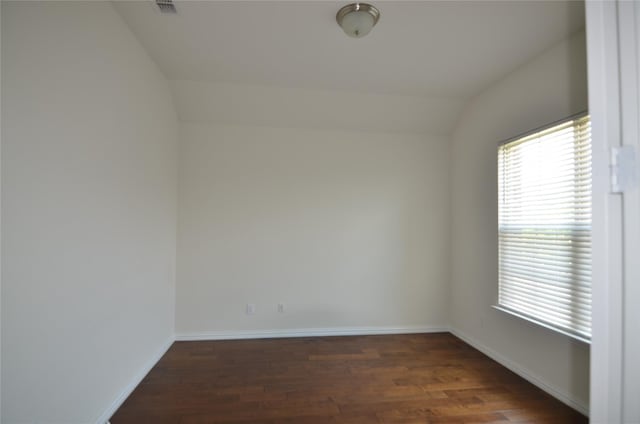 spare room with dark wood-style floors, lofted ceiling, and baseboards