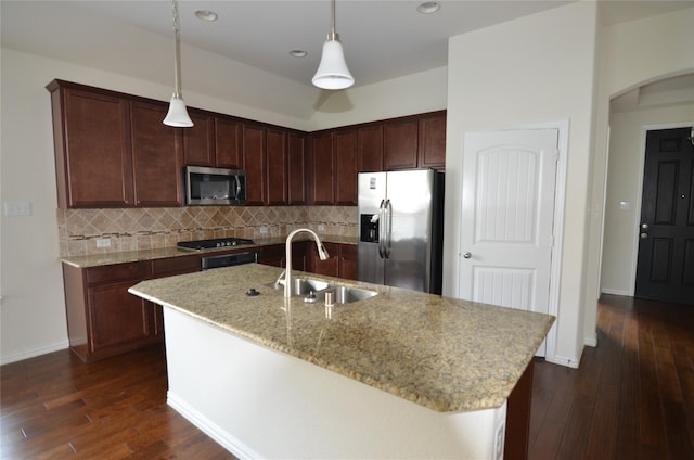 kitchen with appliances with stainless steel finishes, a sink, dark wood-style floors, and tasteful backsplash