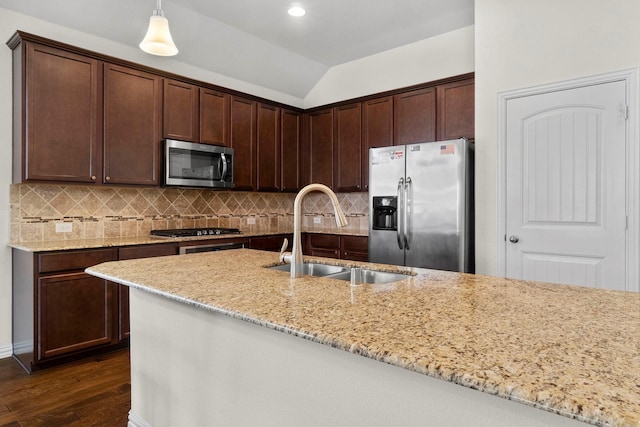 kitchen with appliances with stainless steel finishes, vaulted ceiling, a sink, and backsplash