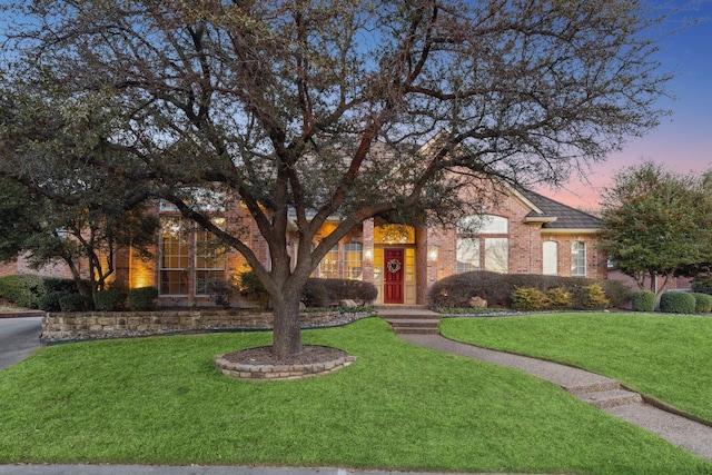 view of front of house with brick siding and a front lawn