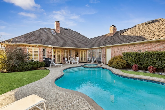 view of pool featuring a patio, french doors, a lawn, and a pool with connected hot tub