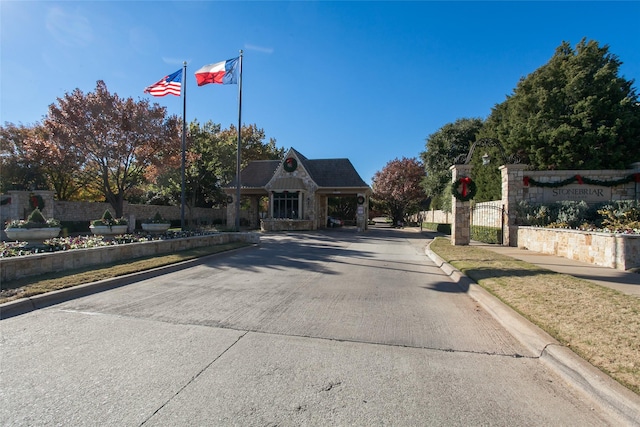 view of street featuring a gate, a gated entry, and curbs