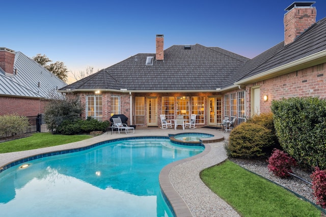 view of pool with a pool with connected hot tub, fence, and a patio