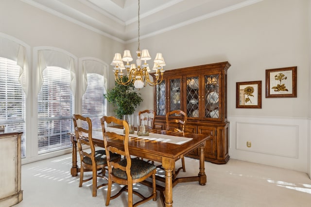 dining room featuring carpet, ornamental molding, a chandelier, and a decorative wall