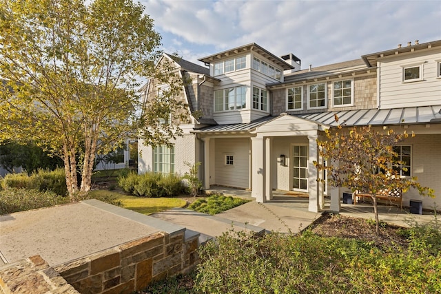 view of front of house with a standing seam roof, brick siding, and metal roof