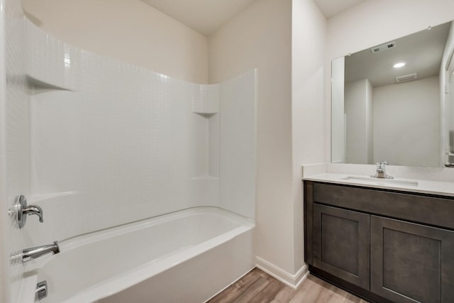 bathroom featuring wood finished floors, visible vents, vanity, baseboards, and shower / washtub combination