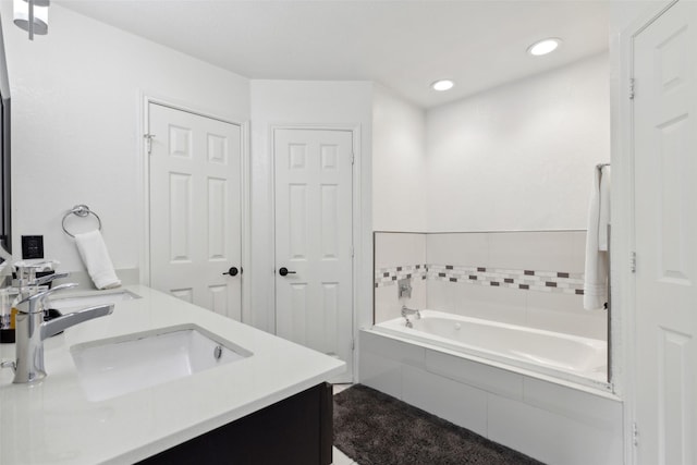 full bathroom featuring double vanity, a sink, a bath, and recessed lighting