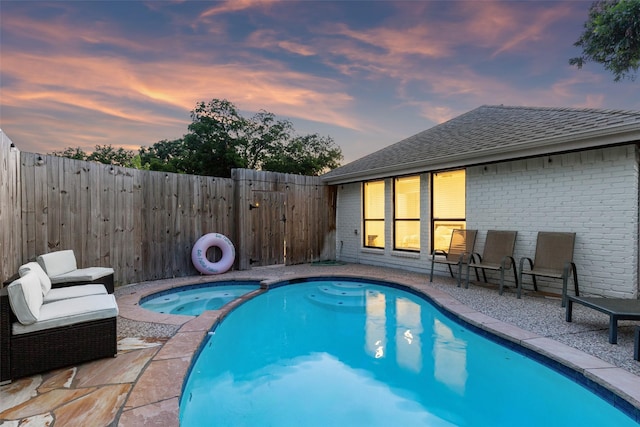 view of swimming pool with a pool with connected hot tub, a patio area, and fence