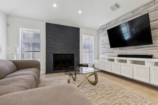 living room featuring lofted ceiling, a fireplace, visible vents, and recessed lighting