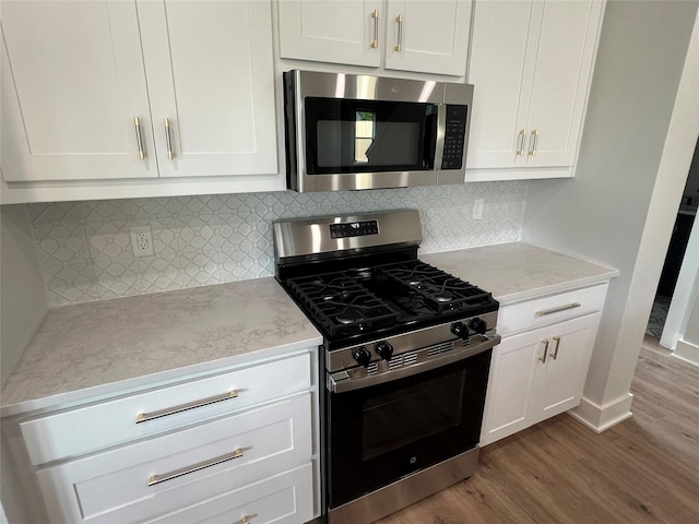 3244 Crites St, Richland Hills, TX 76118 - kitchen featuring stainless steel appliances, wood finished floors, white cabinetry, light stone countertops, and decorative backsplash
