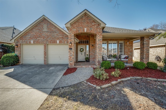 view of front of home with driveway, a shingled roof, an attached garage, a porch, and brick siding