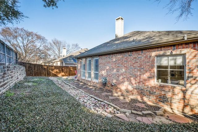 back of property featuring a fenced backyard, brick siding, and a chimney