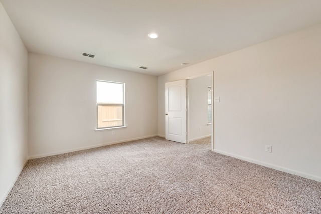 unfurnished room with baseboards, visible vents, and light colored carpet