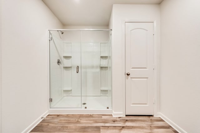 bathroom featuring a stall shower, baseboards, and wood finished floors