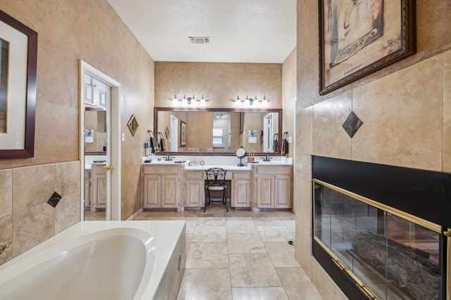 bathroom with a garden tub, double vanity, and a textured ceiling