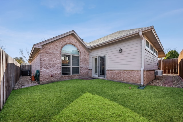 rear view of property with a yard, brick siding, and a fenced backyard