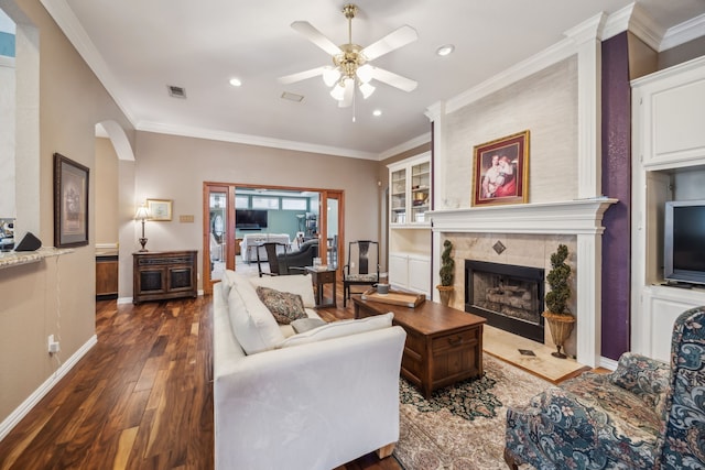 living room with visible vents, ornamental molding, a high end fireplace, dark wood-type flooring, and ceiling fan