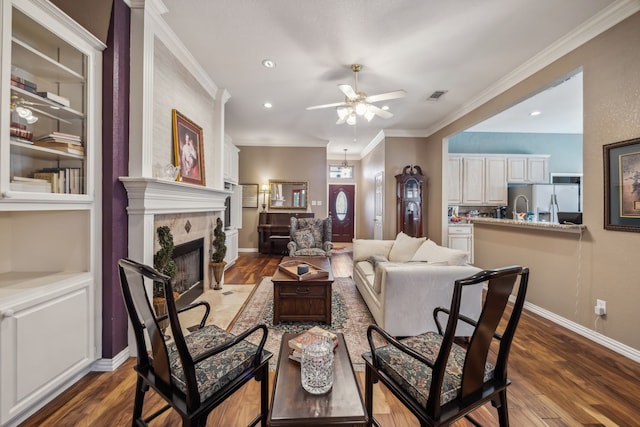 living area featuring ornamental molding, a fireplace, dark wood finished floors, and baseboards