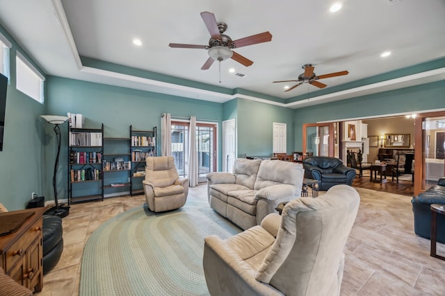 living area with ceiling fan, visible vents, a raised ceiling, and recessed lighting