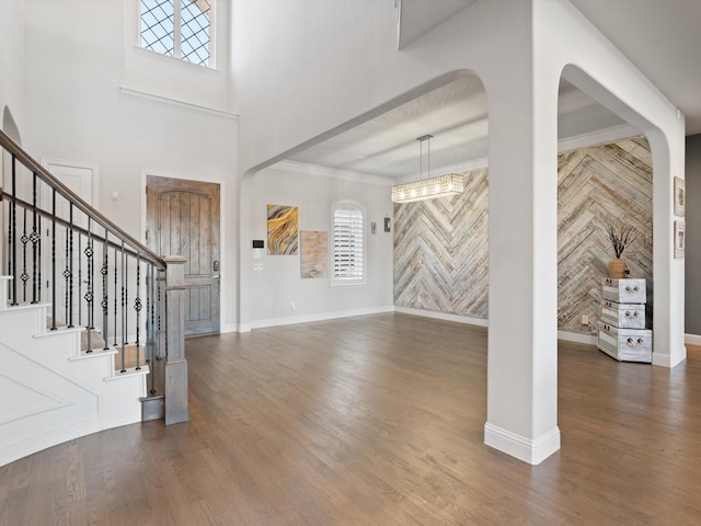 entryway featuring stairs, crown molding, wood finished floors, and baseboards