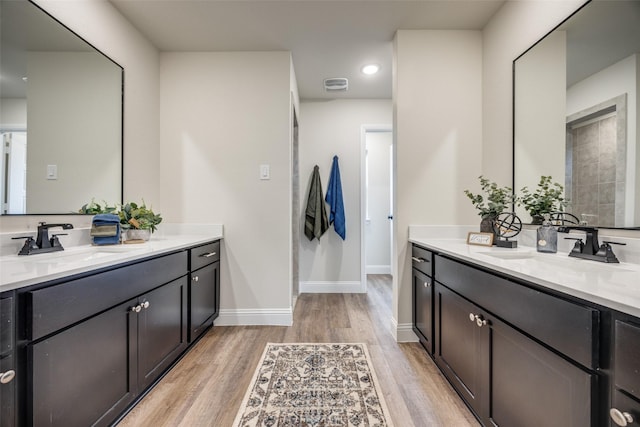 414 Water St, Whitesboro, TX 76273 - bathroom featuring wood finished floors, two vanities, baseboards, and recessed lighting