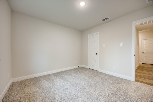 empty room featuring light colored carpet, visible vents, and baseboards