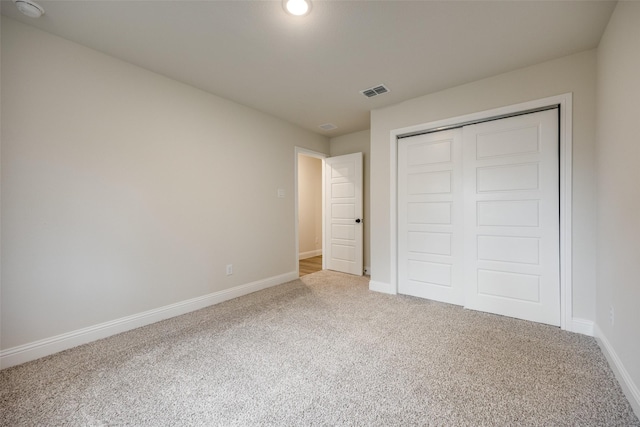 unfurnished bedroom featuring carpet, a closet, visible vents, and baseboards