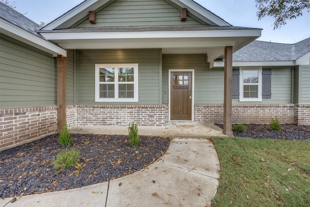 doorway to property with brick siding and roof with shingles