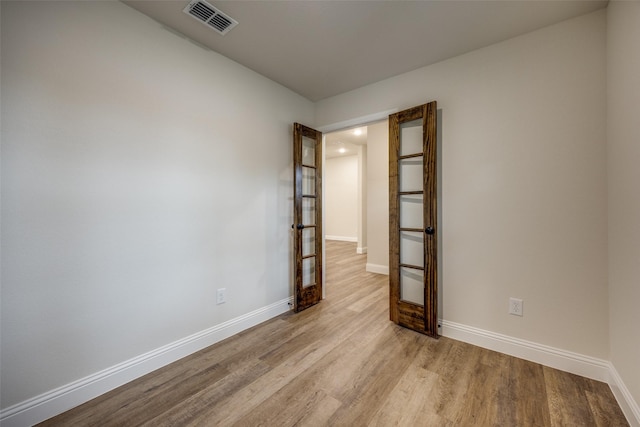 spare room with baseboards, visible vents, and light wood finished floors