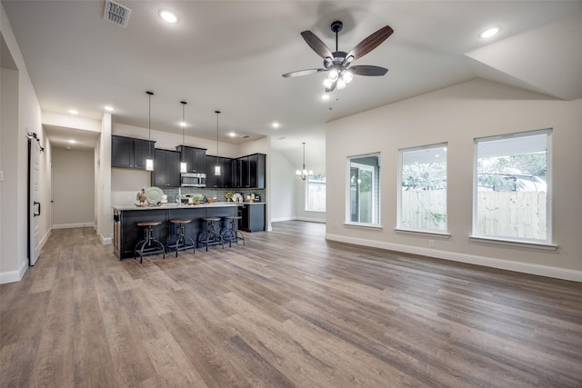 kitchen featuring a breakfast bar area, light countertops, visible vents, stainless steel microwave, and open floor plan