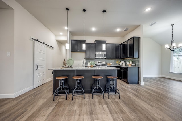 414 Water St, Whitesboro, TX 76273 - kitchen featuring a barn door, stainless steel appliances, baseboards, light wood-style floors, and lofted ceiling